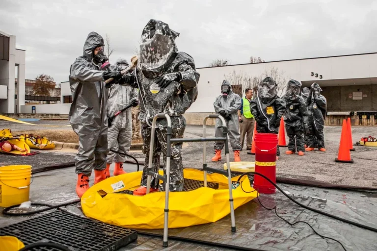 Responders in hazmat suits performing decontamination